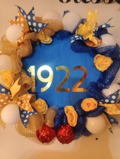 a blue and gold wreath with the number twenty nine on it, decorated with balloons