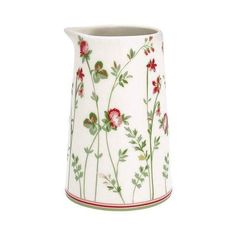 a white vase with red and green flowers painted on the side, sitting in front of a white background