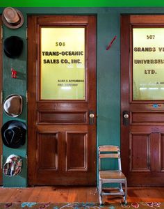 two wooden doors with hats on the wall and a chair in front of one door