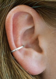 a woman's ear is shown with a thin gold bar on the end of it