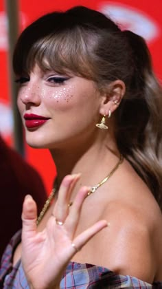 a woman with her hand up in front of her face and wearing red lipstick on the cheek