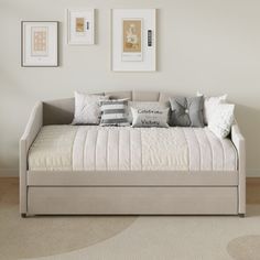 a daybed with pillows and pictures on the wall above it in a living room