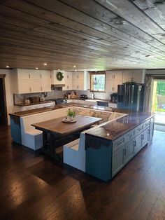 a large kitchen with an island in the middle and wooden flooring on the other side