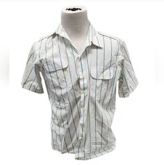 This vintage Oleg Cassini shirt is a stylish addition to any wardrobe. With a blue striped pattern and collared neckline, it's perfect for a retro-themed outfit. The short-sleeved shirt features a button-down closure and pockets for added convenience. Made from breathable woven fabric, it's suitable for all seasons. The size is a regular fit L, and the shirt is designed for men. Whether you're looking for a casual or formal button-up shirt, this Oleg Cassini shirt is a great choice. Blue Collared Shirt With Vertical Stripes, Summer Shirt With Striped Camp Collar, Short Sleeve Shirt With Striped Collar For Work, Striped Short Sleeve Shirt With Camp Collar For Spring, Spring Striped Short Sleeve Shirt With Camp Collar, Cotton Vertical Stripes Collared Shirt, Striped Shirt With Pockets And Spread Collar, Casual Tops With Striped Spread Collar, Spring Horizontal Stripe Collared Shirt