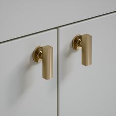 two white cabinets with brass handles and knobs on each door, one is closed