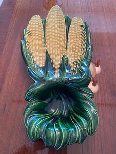 corn on the cob in a green glass vase sitting on a wooden table top