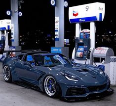 a blue corvette is parked at a gas station