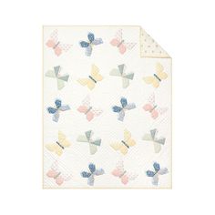 a white quilt with multicolored butterflies on the front and back, in pastel colors