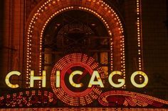 the chicago sign lit up at night in front of an ornate building with lights on it