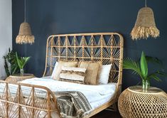 a rattan style bed with pillows and blankets in a blue bedroom decorated with plants