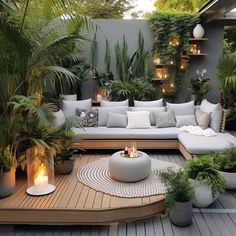 an outdoor patio with lots of plants and candles on the table, surrounded by potted plants