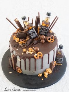 a cake with chocolate icing and nuts on top, topped with bottles of whiskey