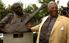 a man standing next to a statue holding a camera