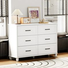 a white dresser sitting next to a window in a room