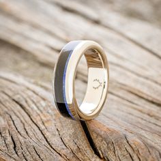 a wedding ring that is sitting on top of a piece of wood with blue and white inlays