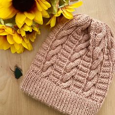 a knitted hat next to sunflowers on a table