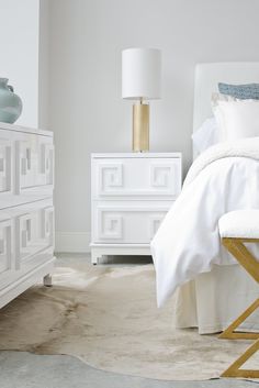 a bedroom with white bedding and gold accents on the nightstands next to it