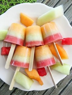 several popsicles are arranged on a plate with watermelon and pineapple slices