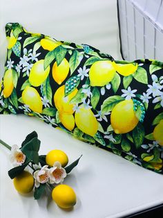 a pillow with lemons on it next to some flowers and a vase filled with fruit