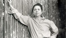 a woman leaning against a wooden wall with her arms outstretched