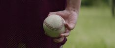 a person holding a baseball in their left hand and wearing a purple shirt on the other