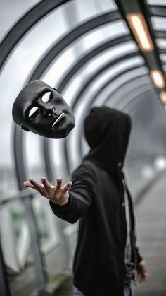 a man in a black hoodie is holding out his hands with a mask on it