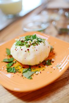 an orange plate topped with food on top of a wooden table