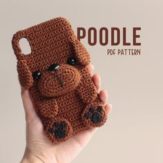 a hand holding up a brown crocheted cell phone case with a dog on it