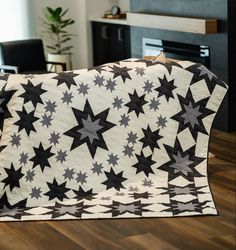 a black and white quilt with stars on it in the middle of a living room