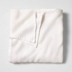 a white blanket folded up on top of a gray surface with an empty pocket in the middle