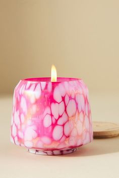 a pink candle sitting on top of a table next to a wooden spoon and plate