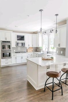 a kitchen with two stools in front of an island and stove top oven on the other side