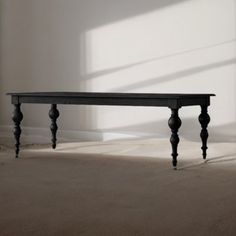 a black table sitting in the middle of a room next to a white wall and floor