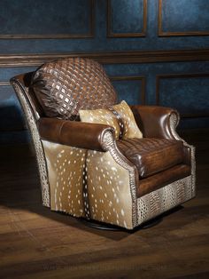 a brown leather chair sitting on top of a wooden floor next to a blue wall