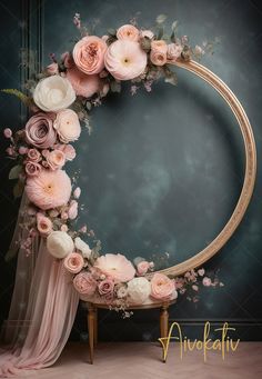 a round wooden frame with pink flowers and greenery around it, sitting on a chair in front of a blue wall