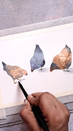 a person is painting three birds with watercolors on paper and using a brush