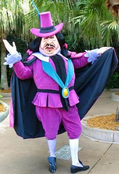 a man dressed in purple and black is posing for the camera with his arms outstretched