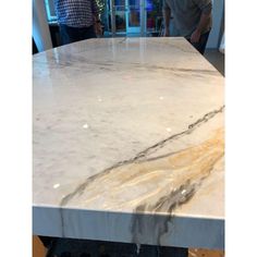 a white marble counter top in a kitchen with people looking at the work area behind it