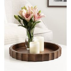 a wooden tray with candles and flowers in it sitting on a table next to a couch