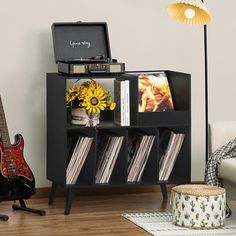 a living room with a guitar, record player and other items on the shelf next to it