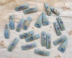 some blue and white flowers are laying on a table cloth next to other pieces of art