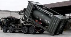 a large dump truck is parked in front of a building with other trucks behind it