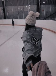 a girl is skating on an ice rink wearing a beanie and holding her hand out