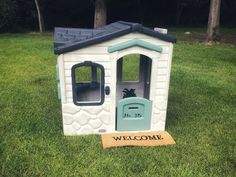 a small white and blue dog house in the grass