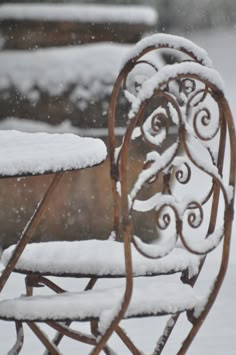 a bench covered in snow sitting on top of a sidewalk