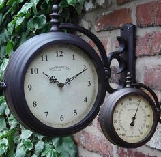 two clocks hanging on the side of a brick wall