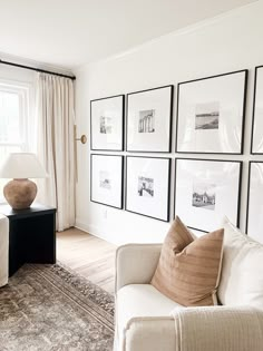 a living room filled with white furniture and pictures on the wall above it's windows