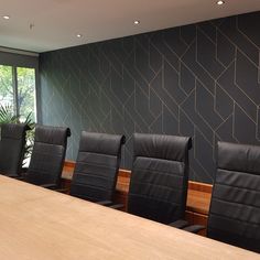 an empty conference room with black leather chairs and wooden tables in front of a large window