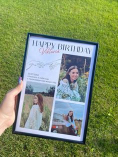 a person holding up a birthday card in the grass