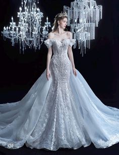 a woman in a white wedding dress standing next to a chandelier with lights